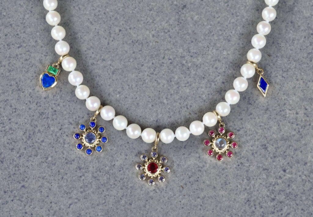 The Akoya pearl strand with the Tillya Tepe Heart Charm, Lapis and Sapphire Cosmos Charm, Tanzanite and Ruby Cosmos Charm, Ruby and Moonstone Cosmos Charm, and Zan Charm in Lapis Lazuli. Photo by Chloe Beaumont