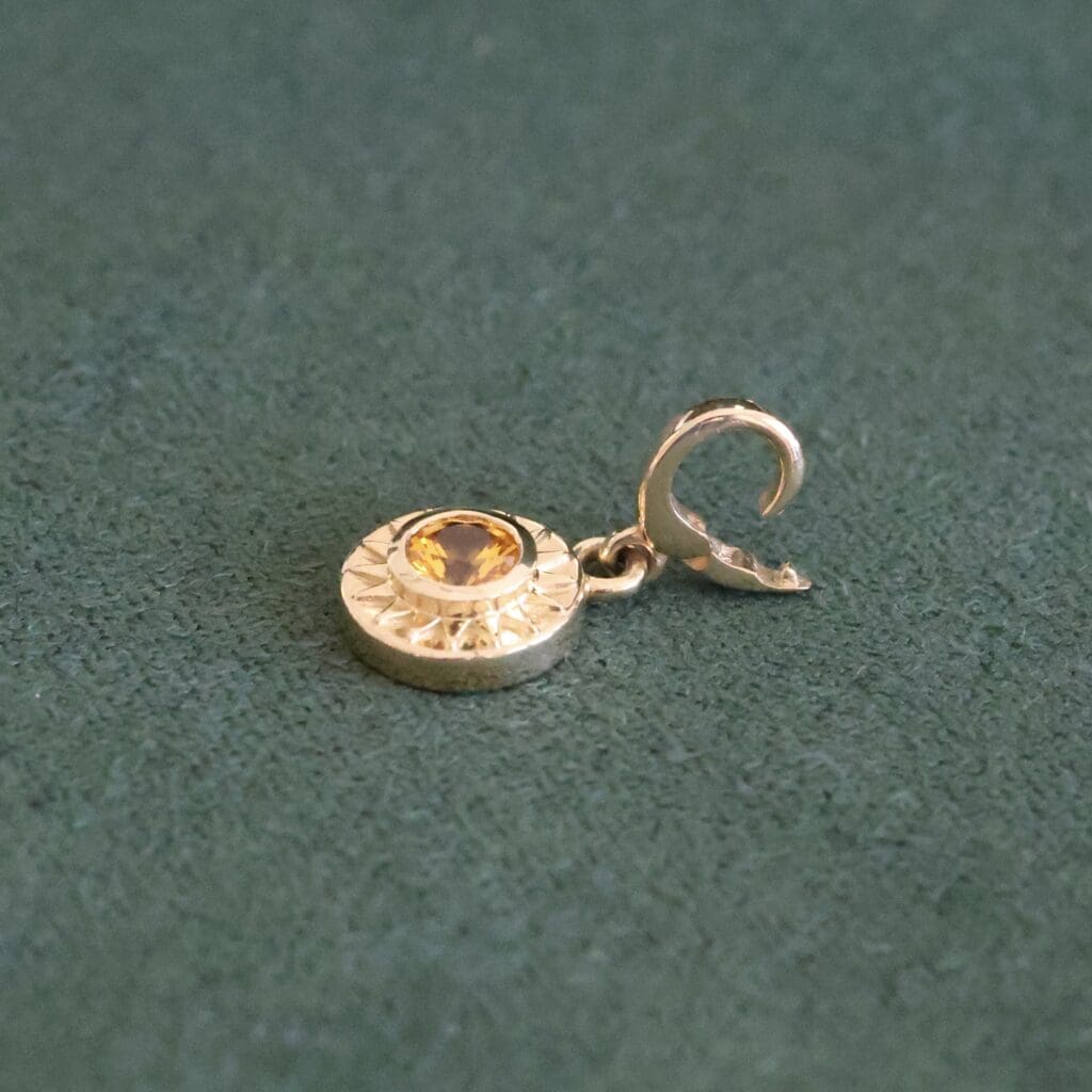 The Sunburst Charm with the bail open, showing how it can snap onto a strand. Photo by Chloe Beaumont